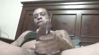 Horny black dude stroking his fat cock while watching porn